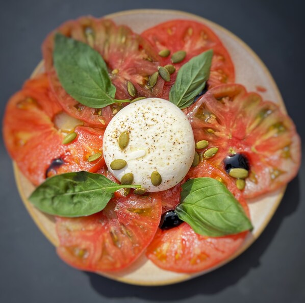 A plate of Caprese salad with tomatoes, mozzarella, basil, and olive oil. - Hotel Escaletto (Aix-en-Provence)