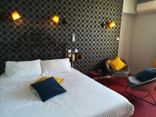 Une chambre d’hôtel avec un lit, deux lampes de chevet, une chaise et une petite table.