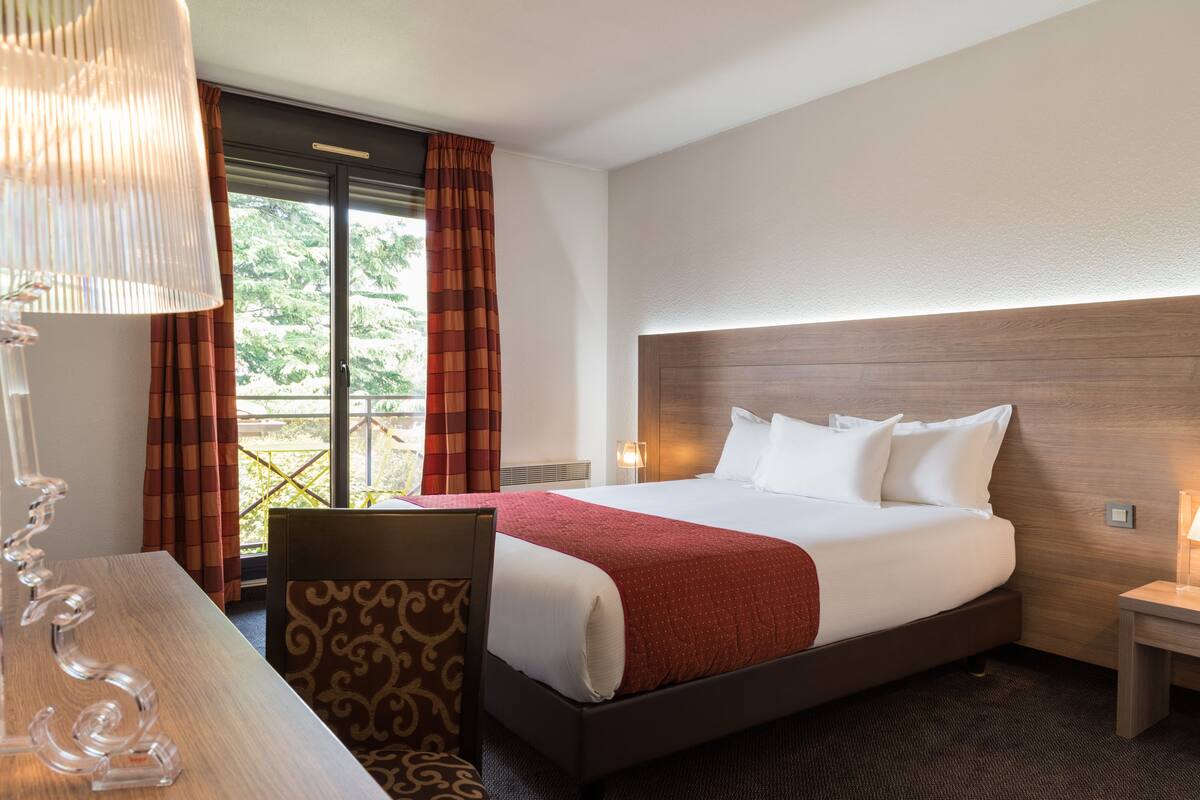 Une chambre d’hôtel avec un grand lit, un bureau et une chaise.