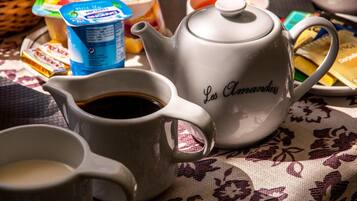 A table with a teapot labeled "Les Amandes," a coffee pot, and various food items including a carton of milk and a container of yogurt.