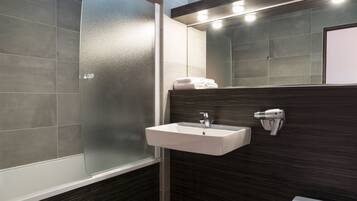 A modern bathroom with a glass shower enclosure, a white sink, and a dark wood vanity.