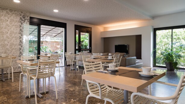 Un café spacieux, doté de nombreuses tables et chaises, de grandes fenêtres et d’un aménagement intérieur moderne.
