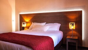 Une chambre d’hôtel avec un grand lit, deux lampes de chevet et un plaid rouge.