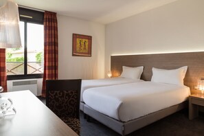 Ein Hotelzimmer mit zwei Betten, einem Schreibtisch und einem Stuhl.