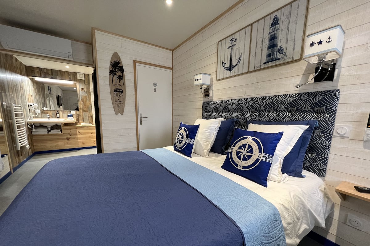 Une chambre avec un grand lit, une tête de lit en bois et une décoration sur le thème de la marine.