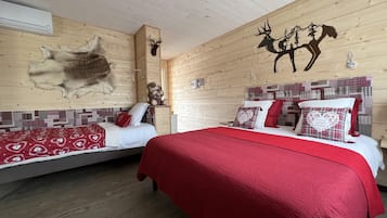 Una habitación acogedora con dos camas, paredes de madera, un trofeo de caza y un cartel de 'No Fumar'.