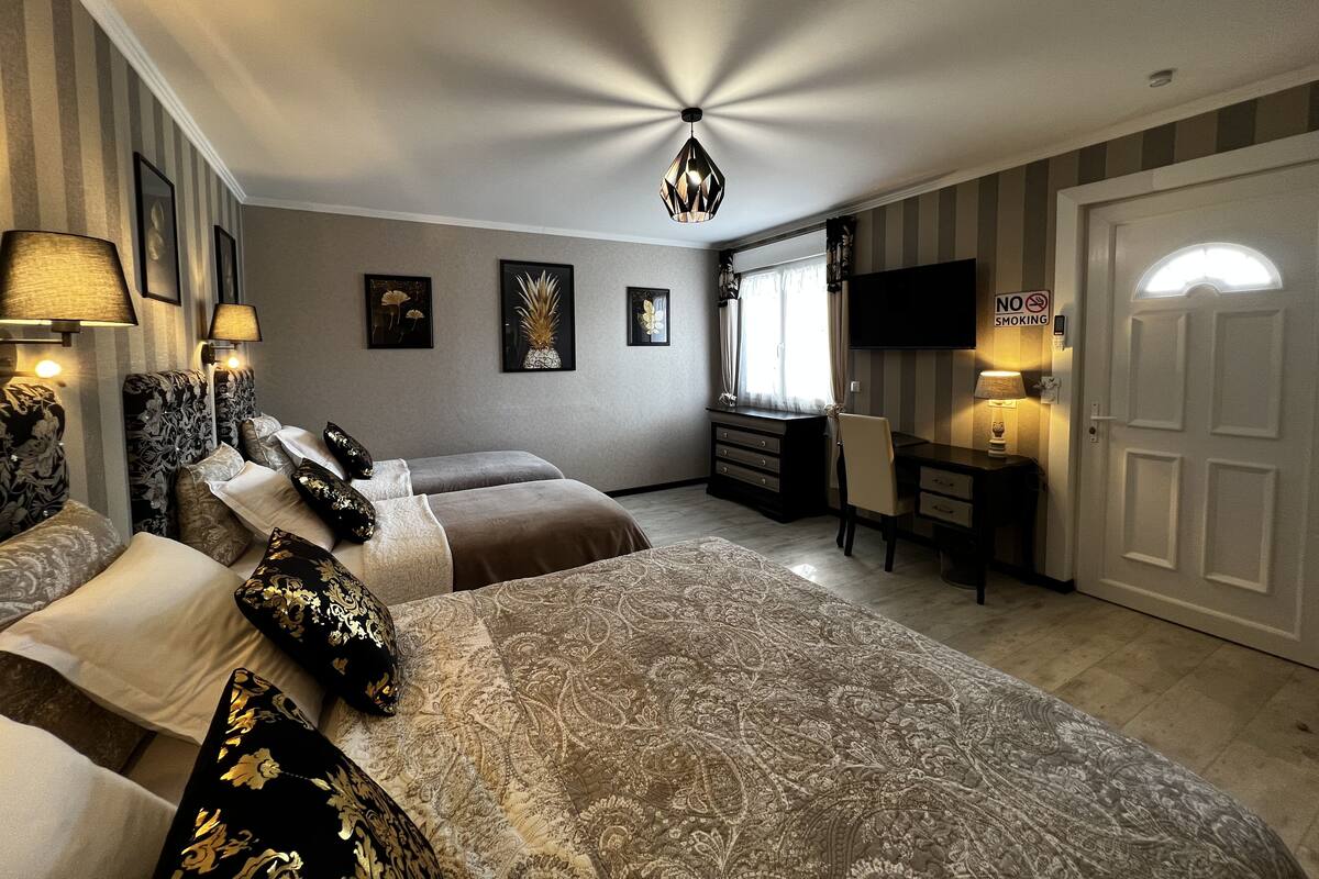 Une chambre d’hôtel avec un grand lit, un bureau, une télévision et un panneau indiquant « Il est interdit de fumer ».