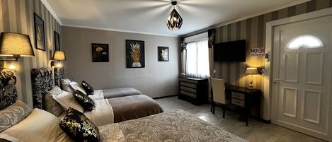 A hotel room with a large bed, a desk, a TV, and a "No Smoking" sign.