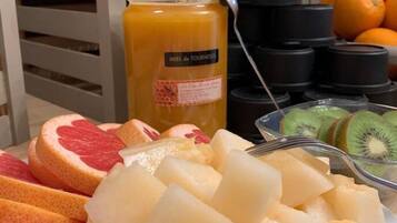 Una mesa con varias frutas y una botella de jugo de naranja.