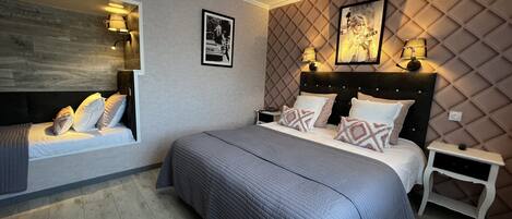 Un dormitorio moderno con una cama grande, un banco empotrado junto a la ventana y un panel decorativo en la pared.