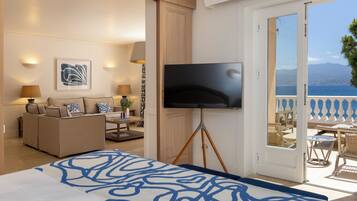 A hotel room with a bed, a TV on a stand, a sofa, a table, and a balcony with a view.