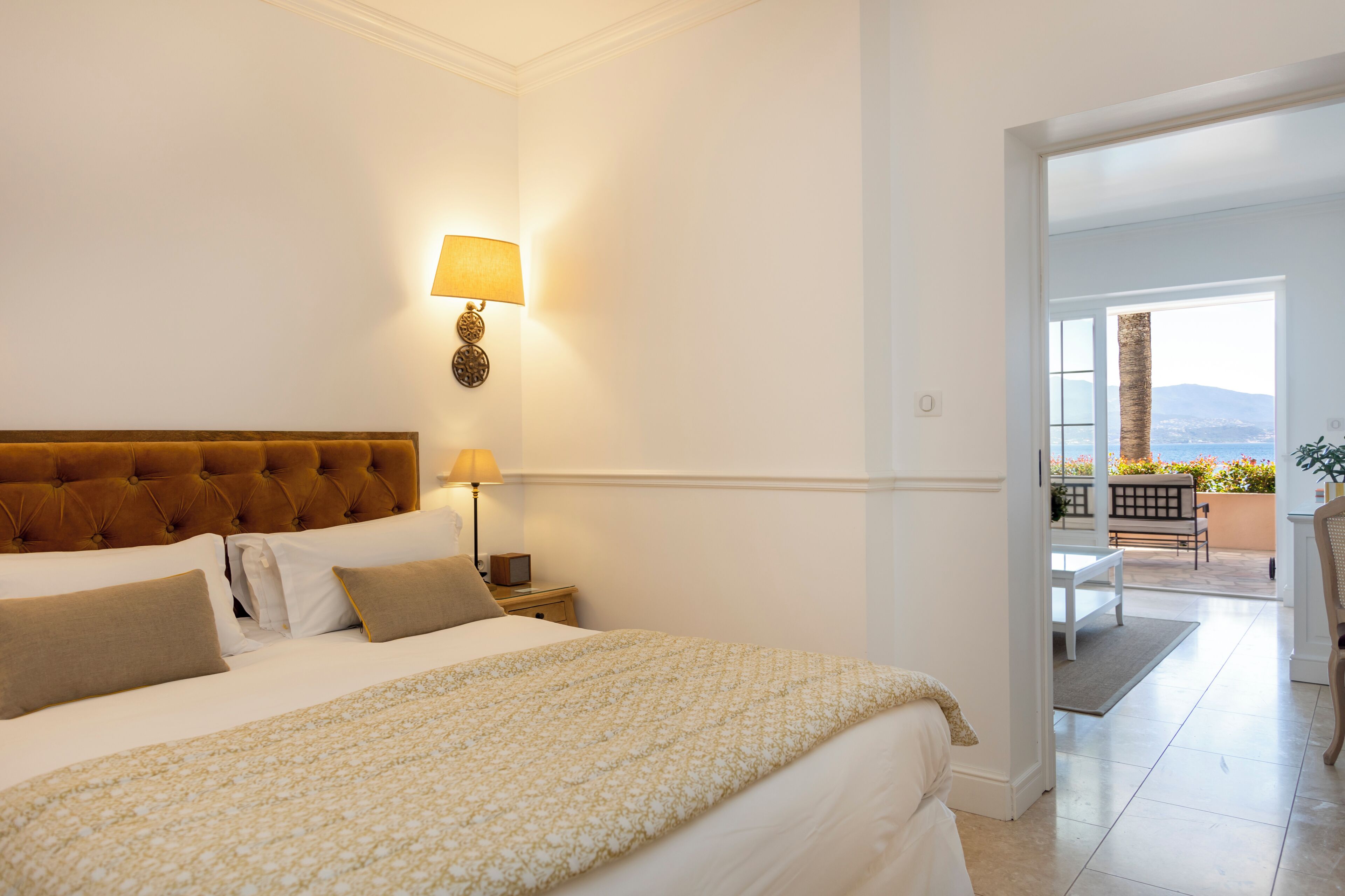 Habitación de hotel con una cama grande, una lámpara de noche, una mesita de noche y vistas al exterior.