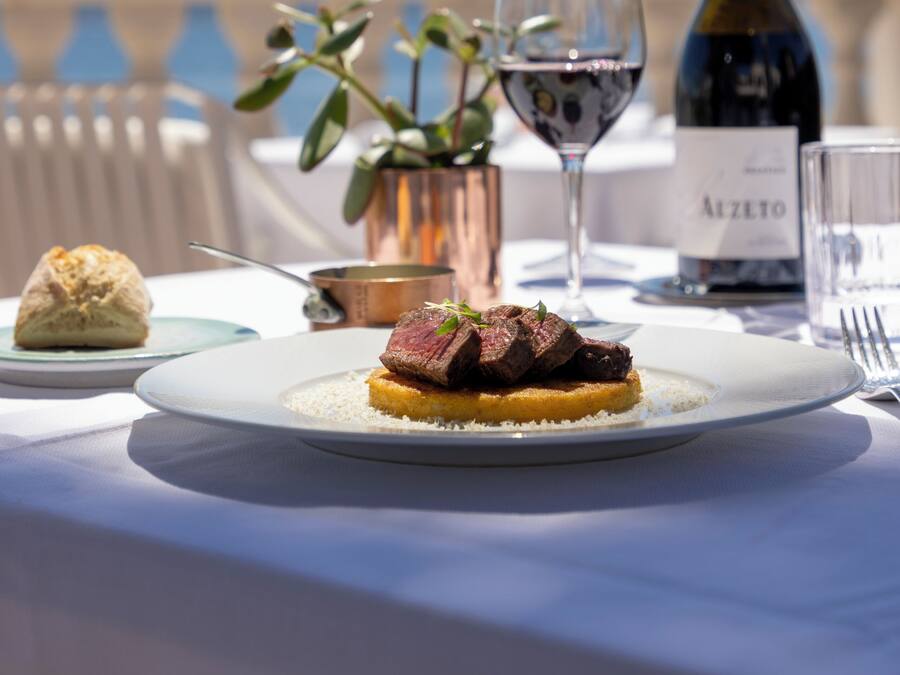 Uma mesa de jantar com um prato de comida, um copo de vinho e uma garrafa de vinho.