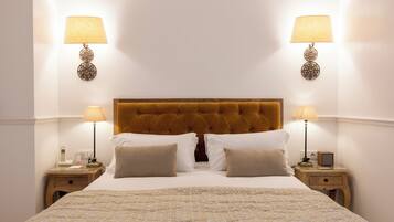 Un lit bien fait, recouvert d’une couvre-lit à motifs, avec deux lampes de chevet, un téléphone et une petite table de chaque côté.
