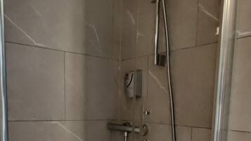 Un box de ducha moderno con un cabezal de ducha de mano y un panel de control en la pared.