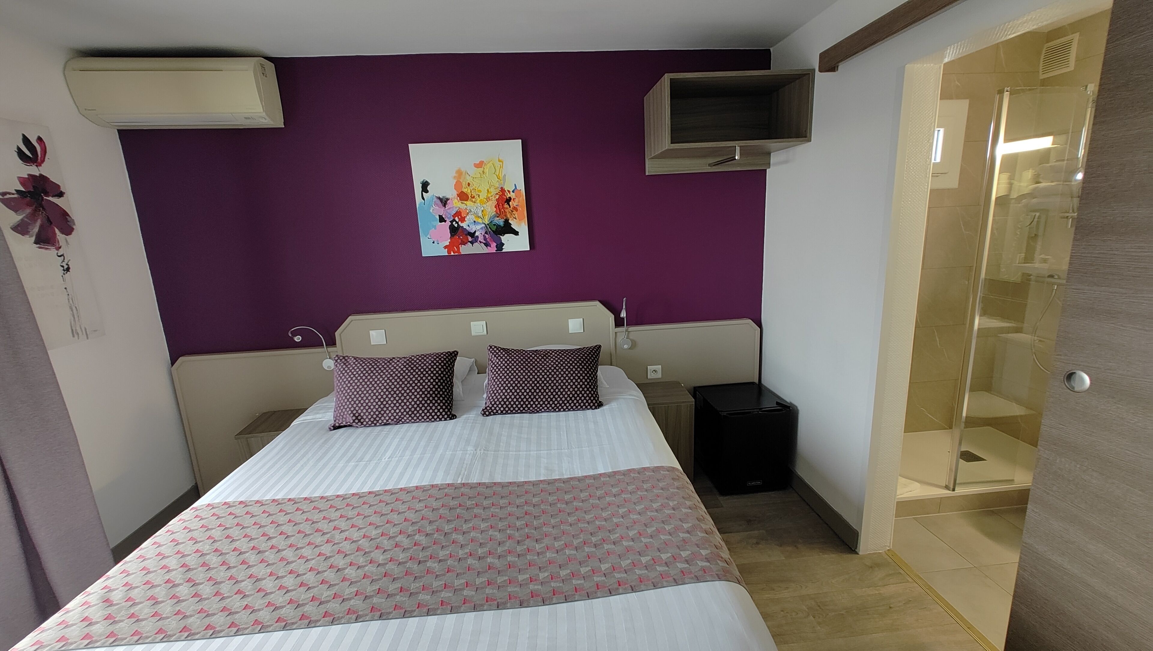 A bedroom with a bed, a nightstand, a TV, and a bathroom door.