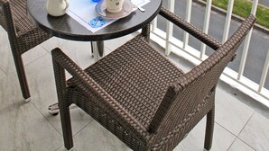 A balcony with wicker furniture, a table set with cups and saucers, and a view of the beach and ocean. - Logis Hotel Les Bleuets (Royan)