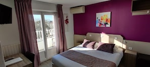 Un dormitorio con cama, escritorio y ventana con cortinas.