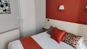 Une chambre d’hôtel avec un lit, un radiateur, une porte et un mur orné d’une roue décorative et de deux lampes murales.