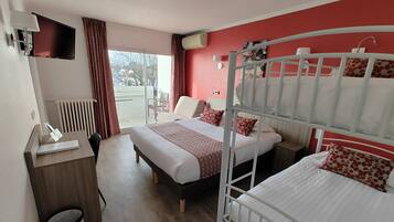 Quarto de hotel com duas camas, uma escrivaninha, uma cadeira, um radiador e vista para o exterior.