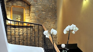 Un escalier avec un mur en pierre, une rampe en bois et un mur blanc orné d’un miroir.