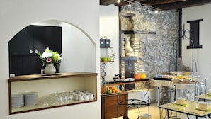 Un coin petit-déjeuner avec un mur en pierre, un meuble noir et une table mise pour le petit-déjeuner.