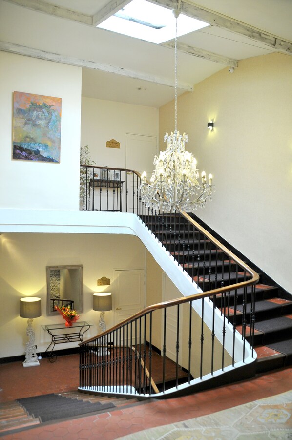 Un intérieur à plusieurs niveaux, agrémenté d’un escalier, d’un lustre et d’œuvres d’art.