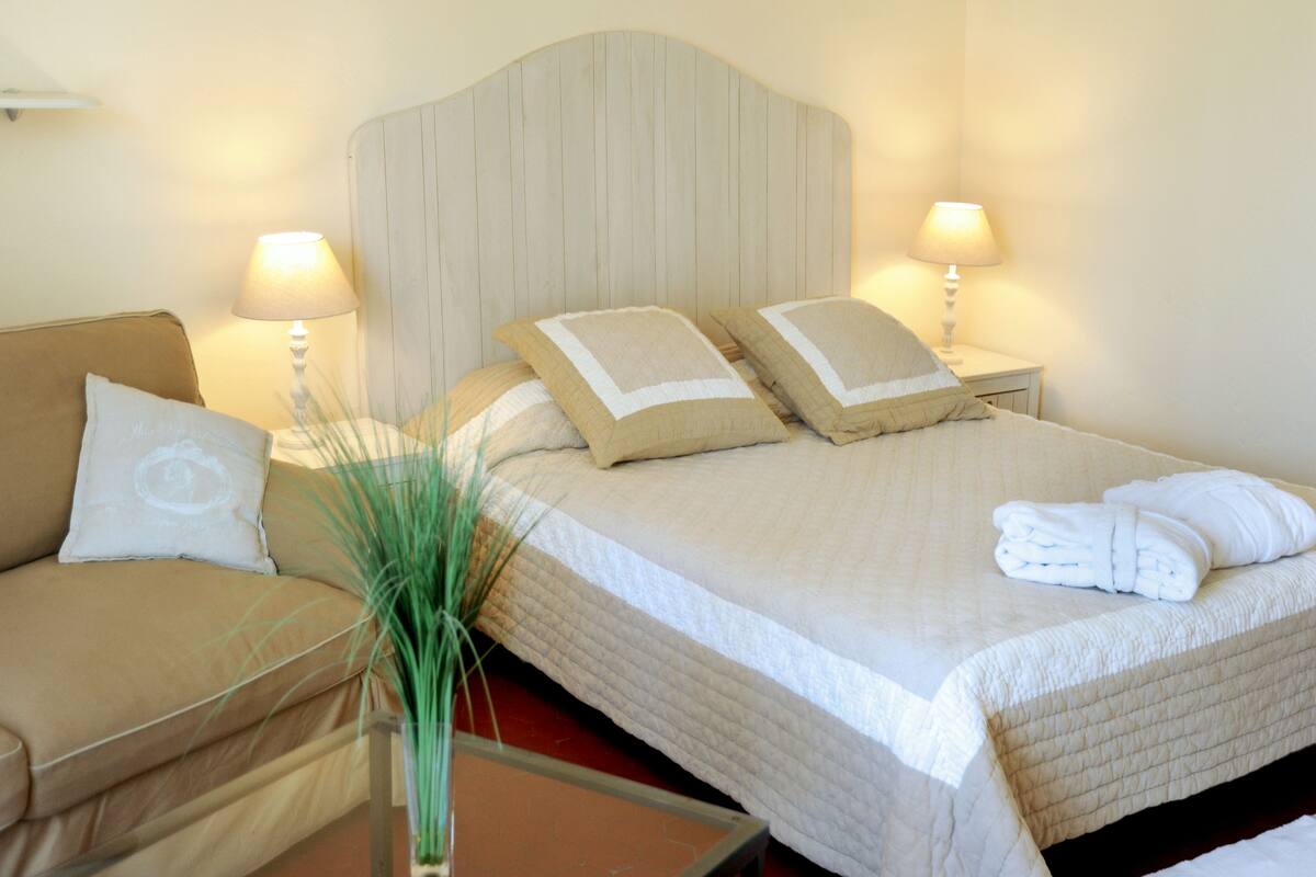 A neatly made bed with pillows, a bedside lamp, and a small potted plant.
