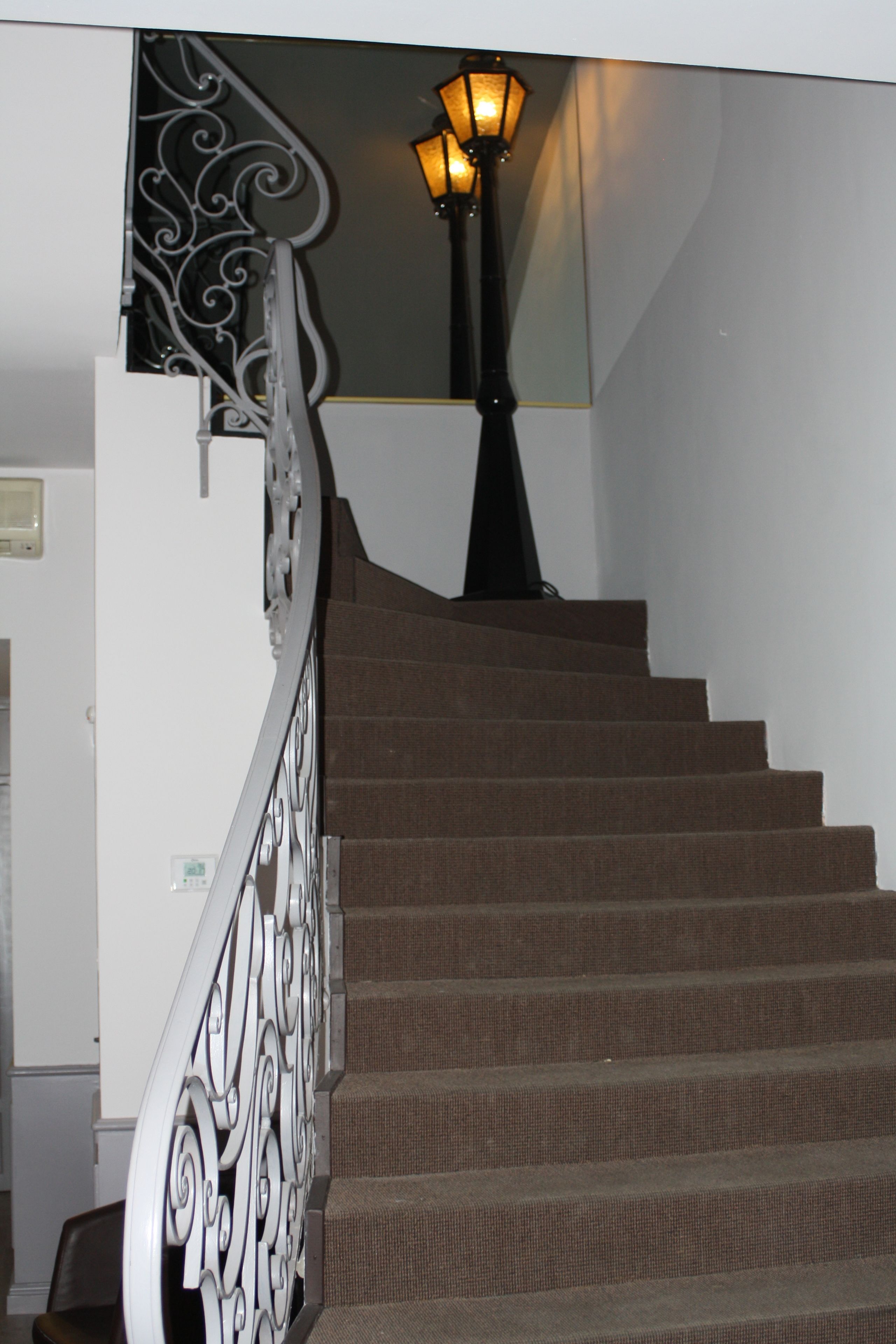 A staircase with a metal railing and a wall-mounted light fixture.