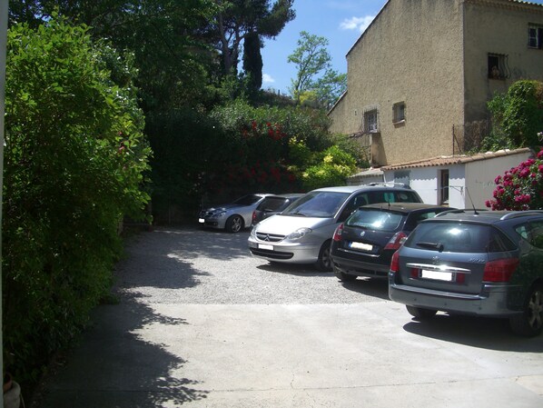 A parking area with several cars parked in front of a building with a tiled roof. - Hôtel du Midi (Salon-de-Provence)
