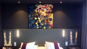 Una habitación de hotel con una cama grande, dos mesitas de noche y una obra de arte colgada en la pared.