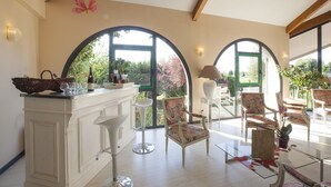 Una habitación amplia con barra blanca, ventanas en arco y vistas al verdor.