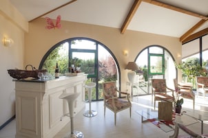 Um quarto espaçoso com um balcão branco, janelas em arco e vista para o verde.