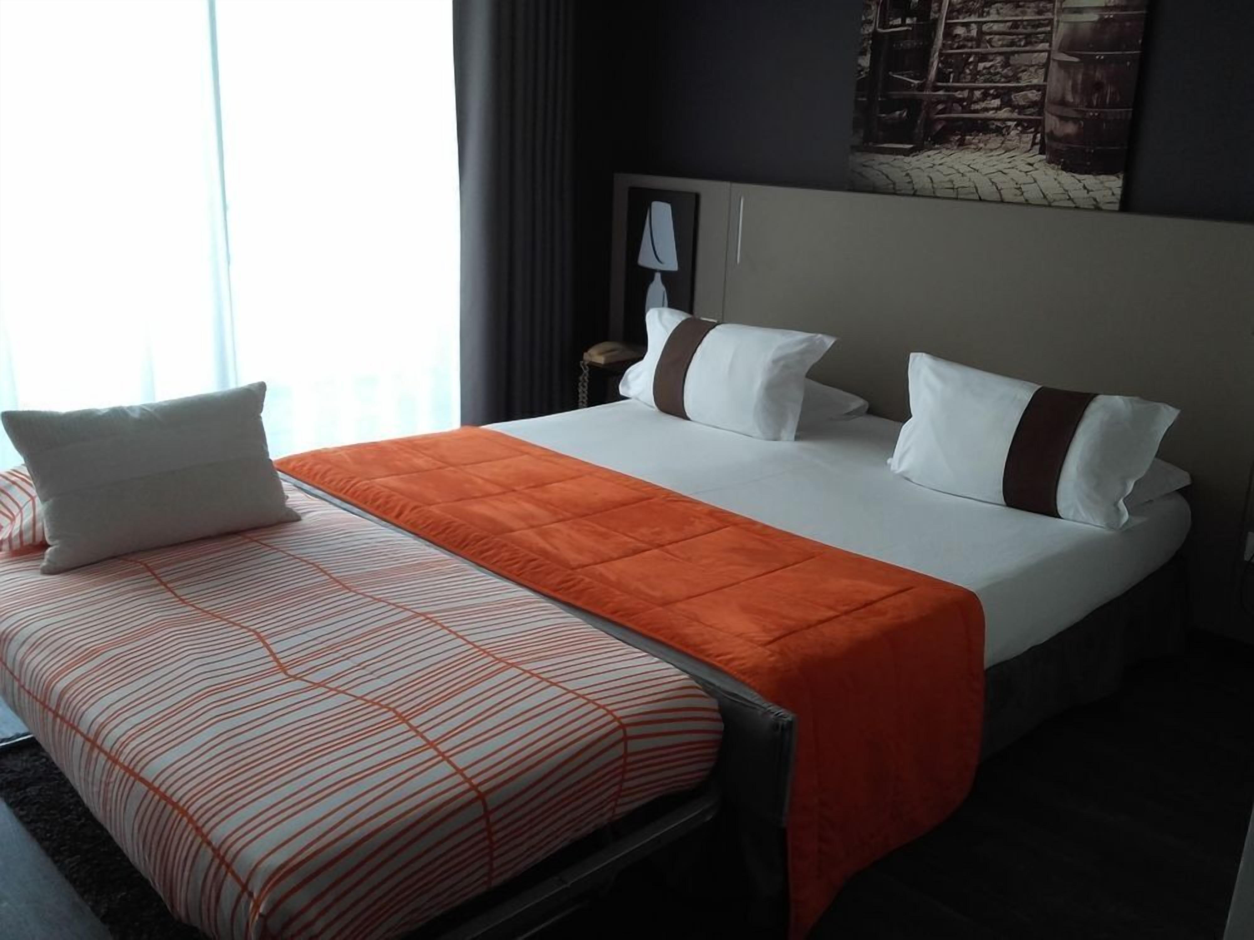 Une chambre d’hôtel avec un lit, une table de chevet et une lampe.