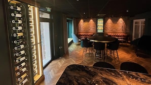 Eine Bar mit einer Marmorplatte, Ledersitzgelegenheiten und einer Flaschenauslage.