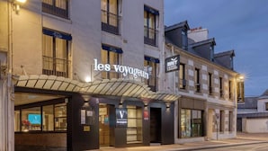 Ein Hotel mit einer klassischen Fassade, mehreren Stockwerken und einem gut sichtbaren Schriftzug 'les voyageurs'.
