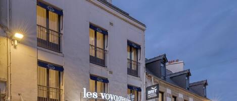 Un hotel con fachada clásica, varios pisos y un llamativo letrero que dice 'les voyageurs'.