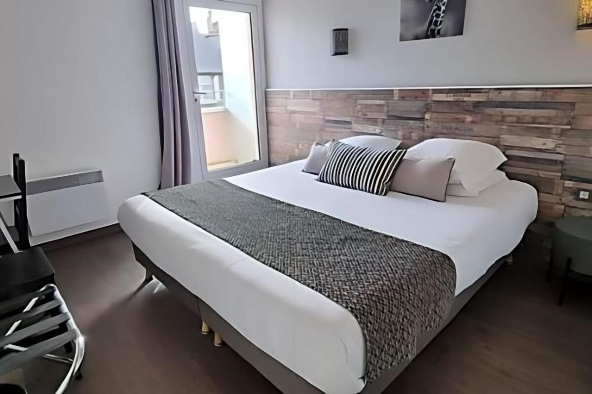 Una habitación de hotel moderna con una cama grande, un escritorio y vistas al exterior.