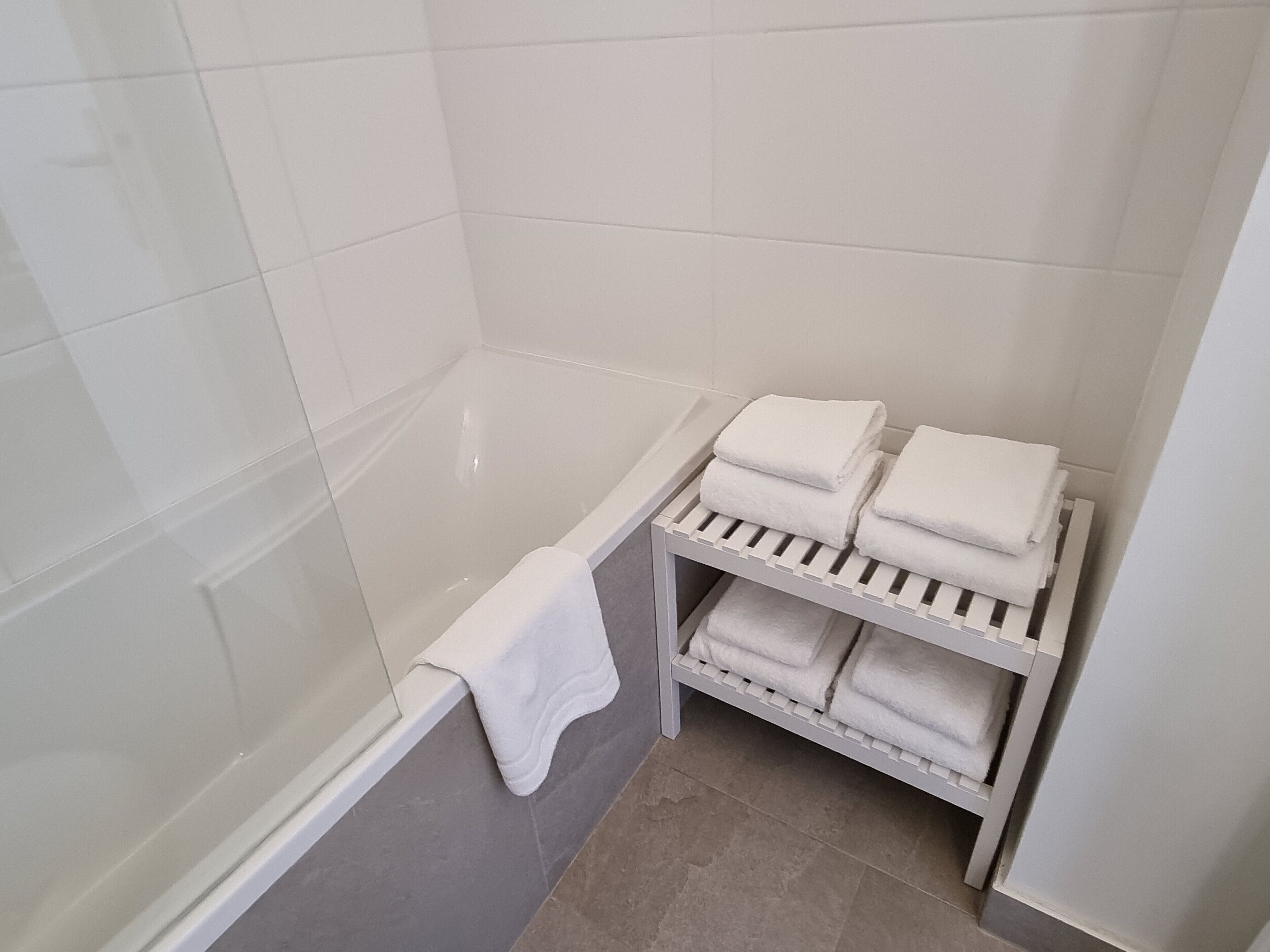 Une salle de bain avec une baignoire, un porte-serviettes avec des serviettes pliées et un rideau de douche.