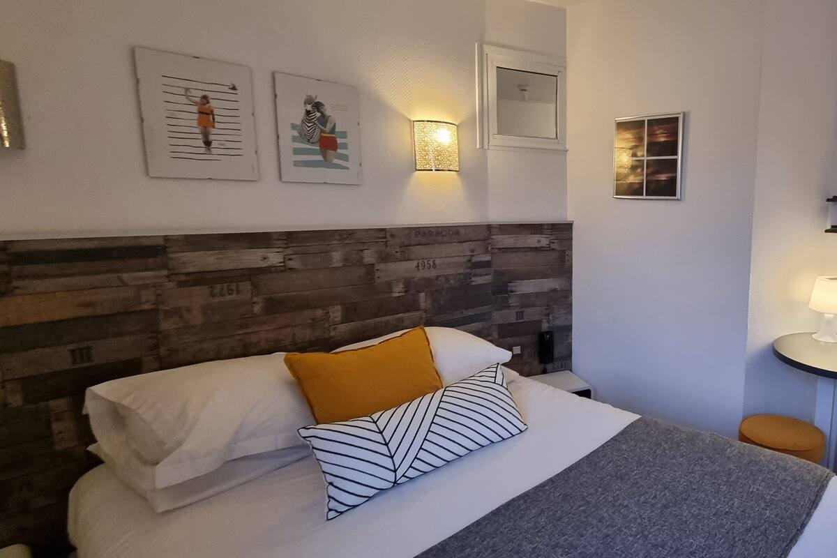 Ein Hotelzimmer mit Bett, Nachttisch, Lampe und einer Wandablage.