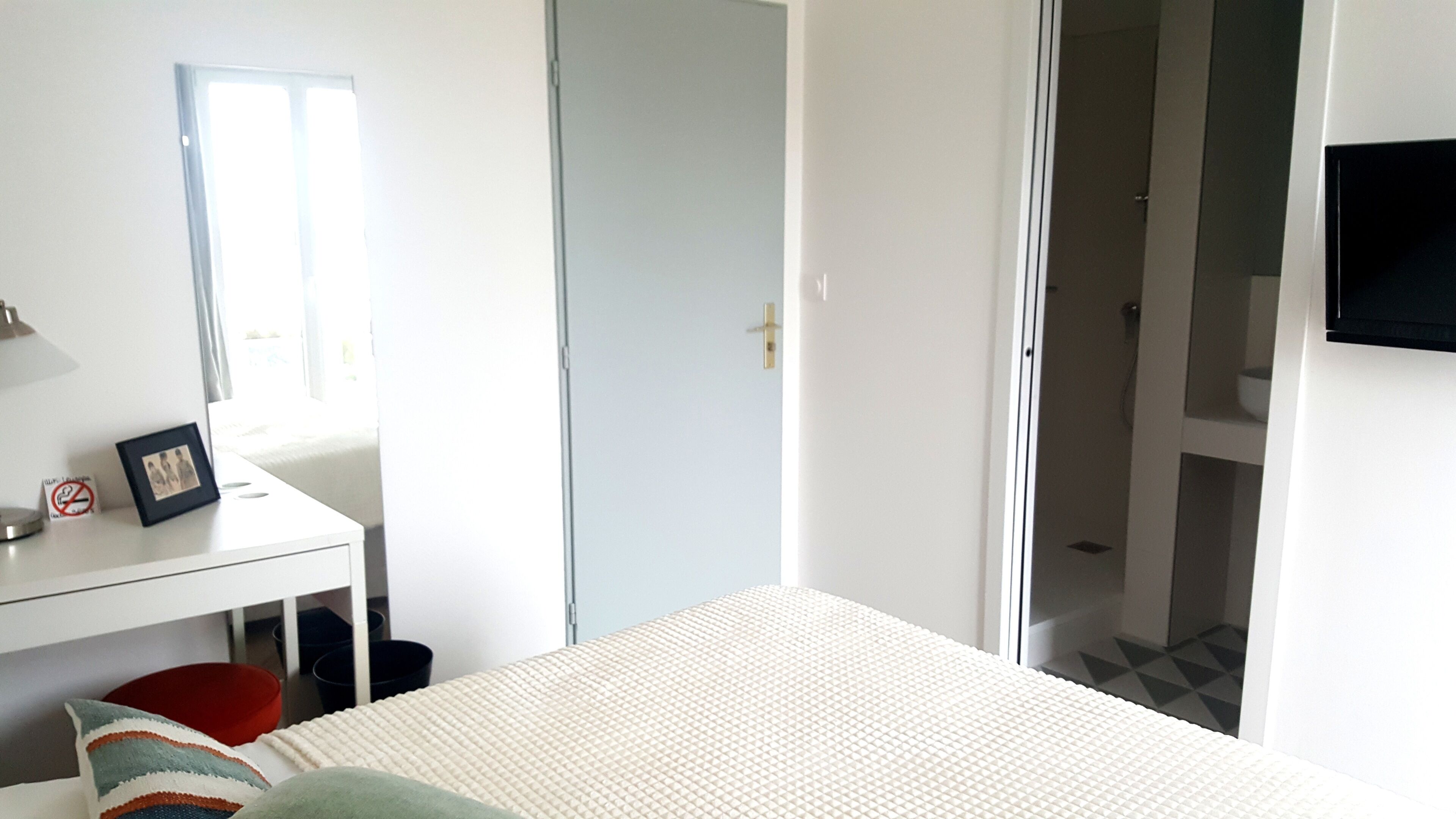 Une chambre à coucher comprenant un lit, un bureau, une chaise, un téléviseur et une porte donnant sur une salle de bain.