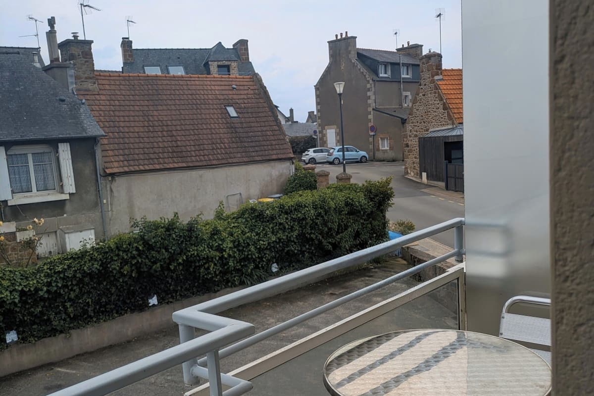 Ein Balkon mit Metallgeländer, einem runden Tisch und einem Stuhl.