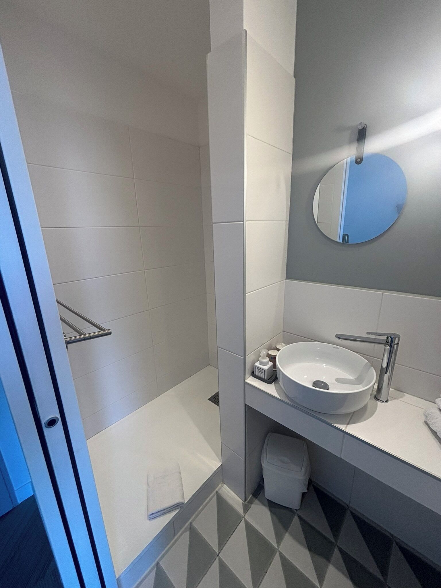A modern bathroom with a white sink, mirror, and tiled floor.