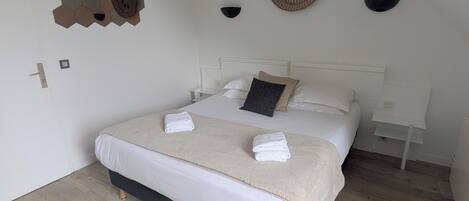 A bedroom with a bed, a wall-mounted decorative item, a ceiling fan, and a light fixture.