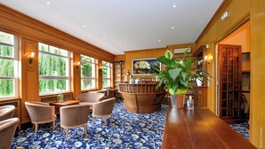 Amplia habitación con ventanas grandes, una zona de bar de madera, sillas de mimbre y un cuadro grande de un leopardo.