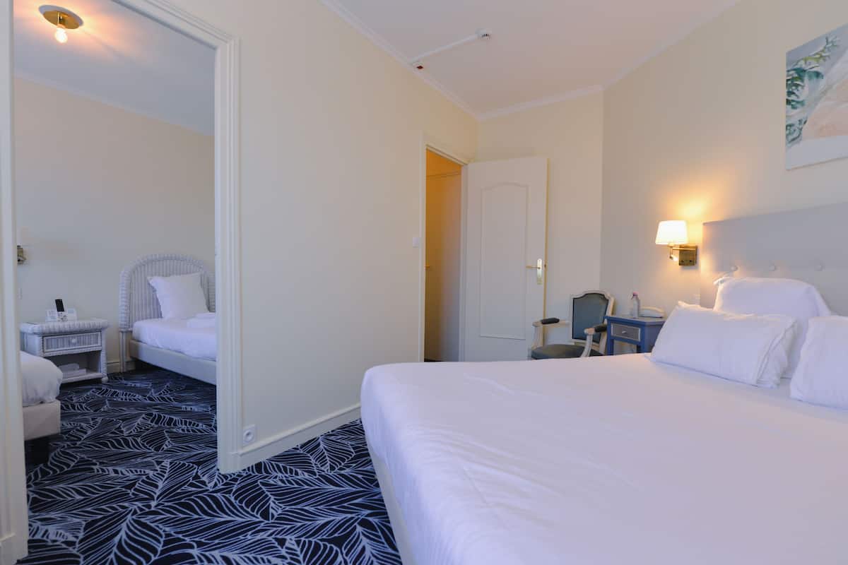 A hotel room with a large bed, a chair, a desk, and a wardrobe.