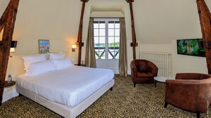 Un dormitorio con cama, una silla, una mesita y una ventana con cortinas.