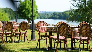 A table set outdoors with wicker chairs and a view of a lake.