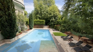 A swimming pool with lounge chairs and a small garden area.
