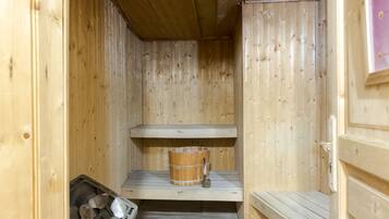 Una sauna de madera con un banco de madera, un cubo y un montón de piedras.